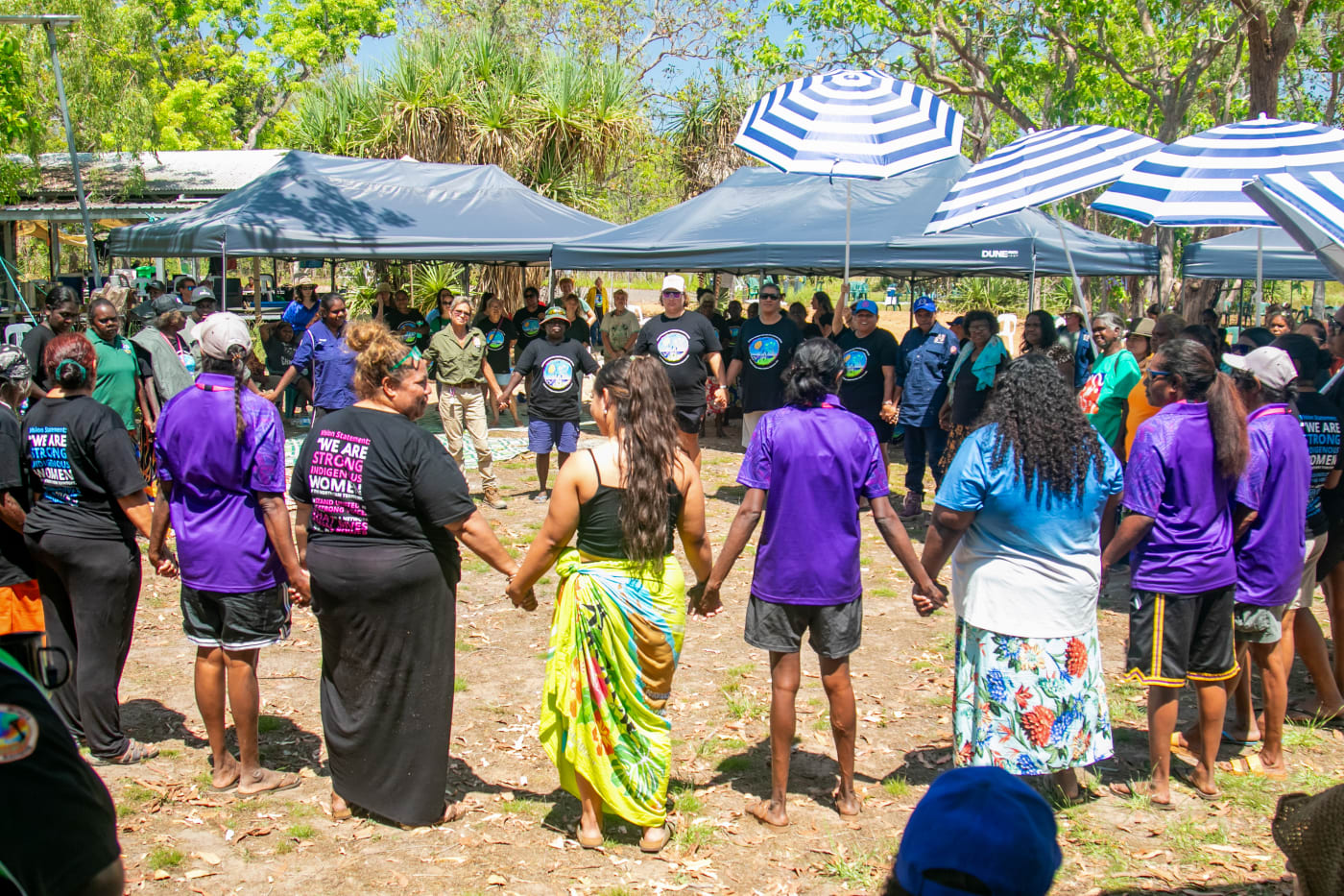 Arrernte woman from Mparntwe (Alice Springs) and Central Land Council member Jody Kopp and her daughter, NT Youth Round Table member and young Arrernte leader Armani Francois join hands with other Message Stick members at the 2023 Strong Women for Healthy Country Forum.