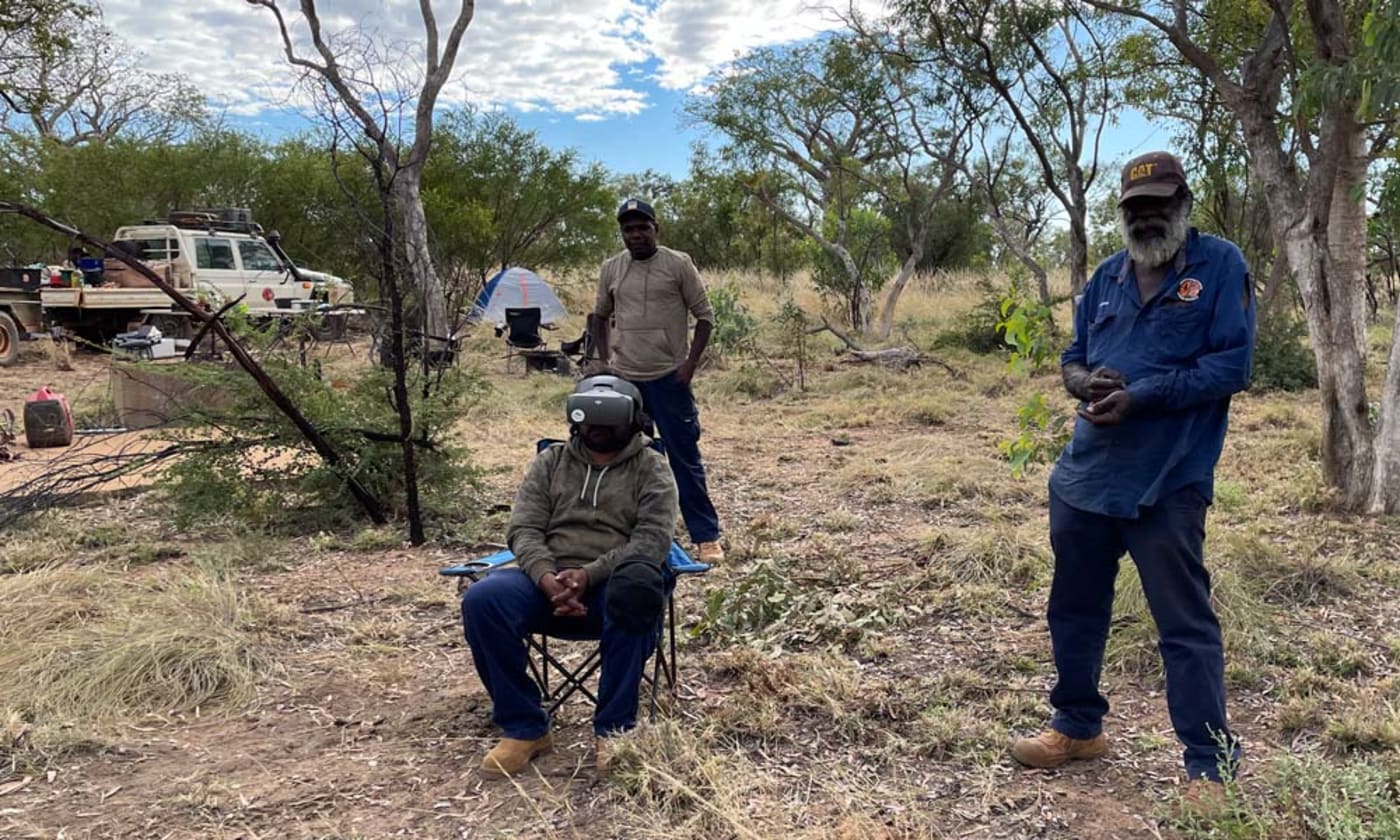 Nyikina Mangala Head Ranger Modra Green (seated) using drone vision goggles to search for wiliji in caves on the Erskine Range while Nyikina Mangala Rangers Vern Chuguna and William Watson watch on