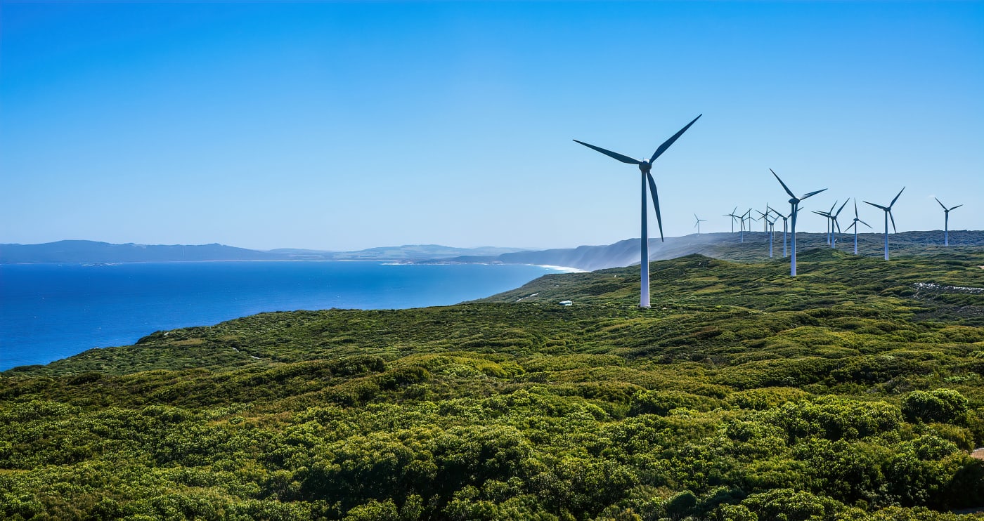 landscape image of a coastline with wind turbines.