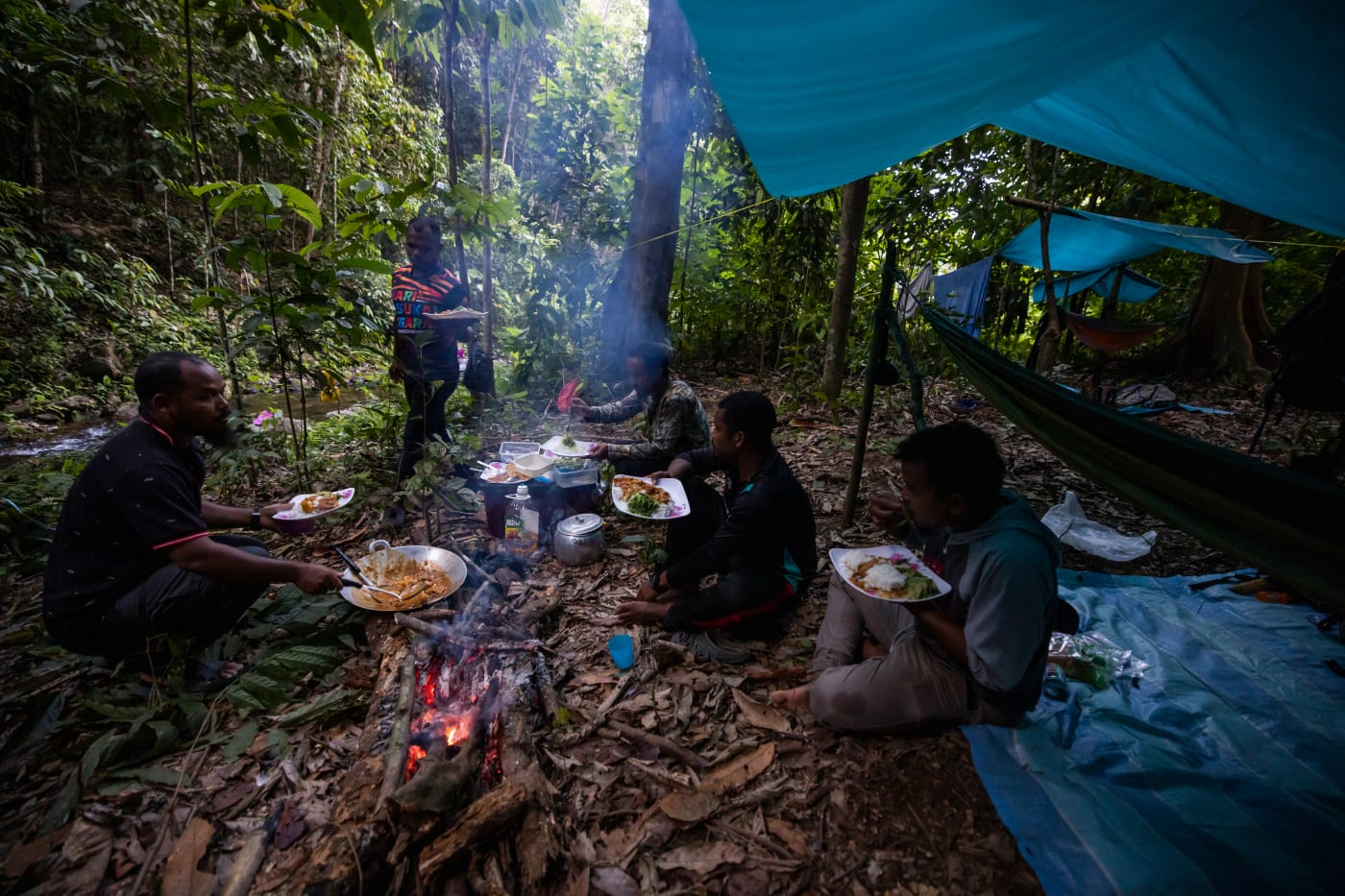An anti-poaching patrol team out on patrol in Malaysia's Royal Belum State Park sits around the campfire and enjoys a well earned evening meal.