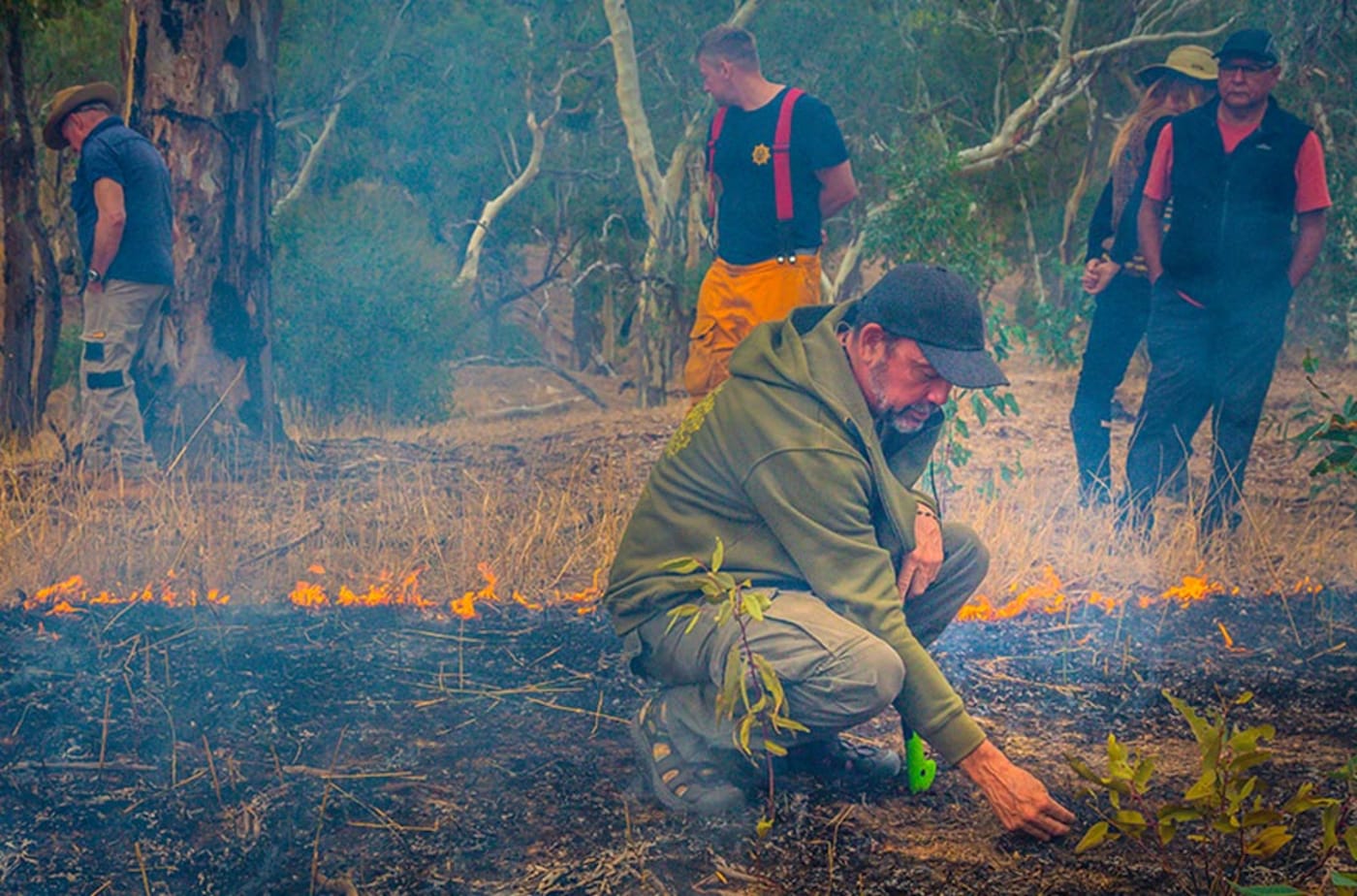 Tagalaka man and Firesticks Alliance Indigenous Corporation’s Lead Fire Practitioner Victor Steffensen crouching within a burn site on Nukunu Country near Beetaloo Reservoir.