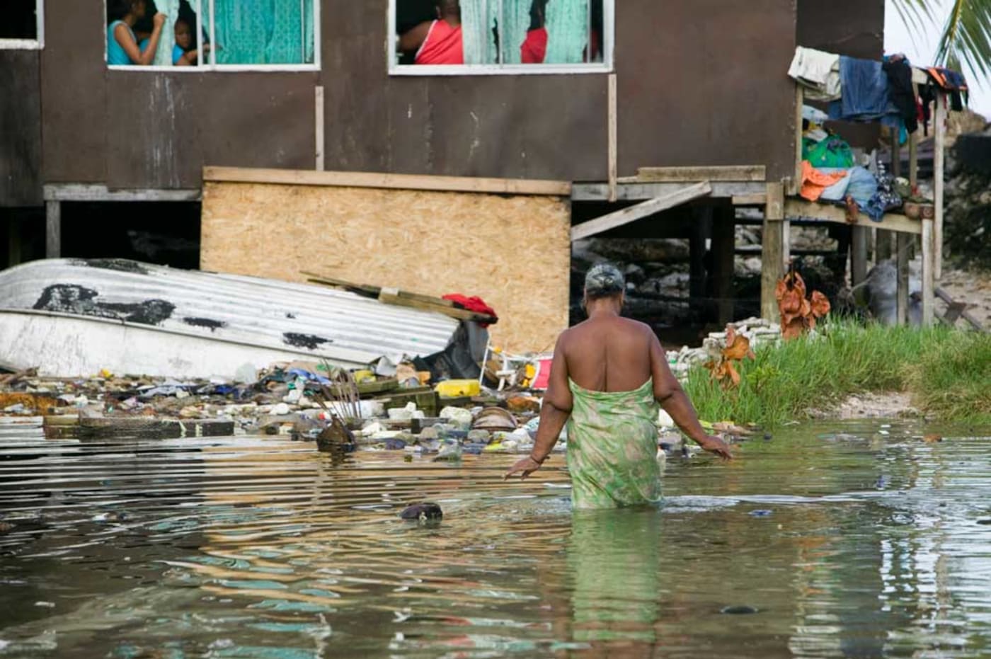 A Tuvaluan women wades through sea water to get to her home, Funafuti atol, Tuvalu