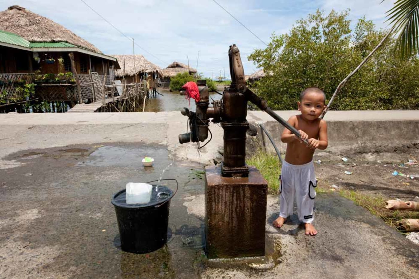 A little boy pumping out water for his bath in Donsol Sorsogon, Bicol, Philippines, May 2009