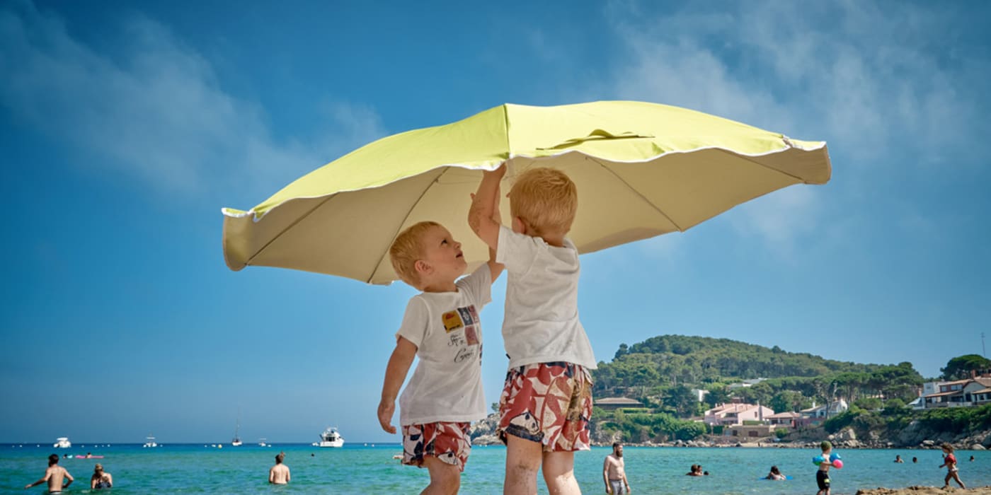Kids under an umbrella at the beach. Photo by Vidar Nordli-Mathisen on Unsplash