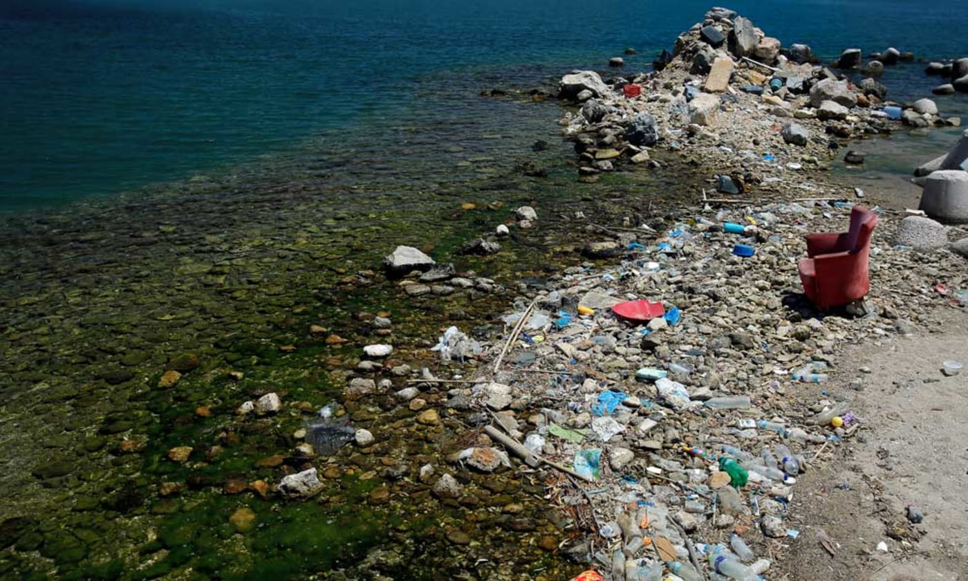 Plastic waste and sofa discarded on a beach in Greece on the Mediterranean Sea