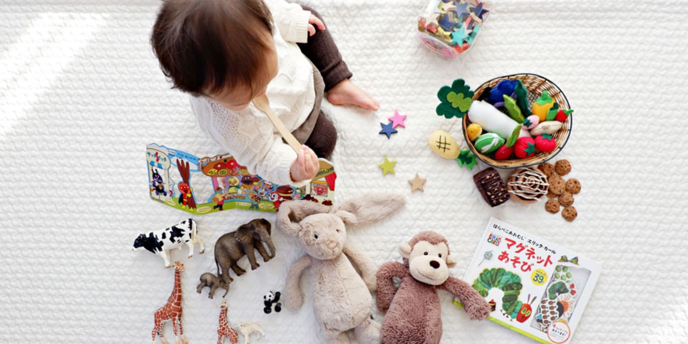 Baby with soft toys= books and wildlife toys. Photo by li tzuni on Unsplash