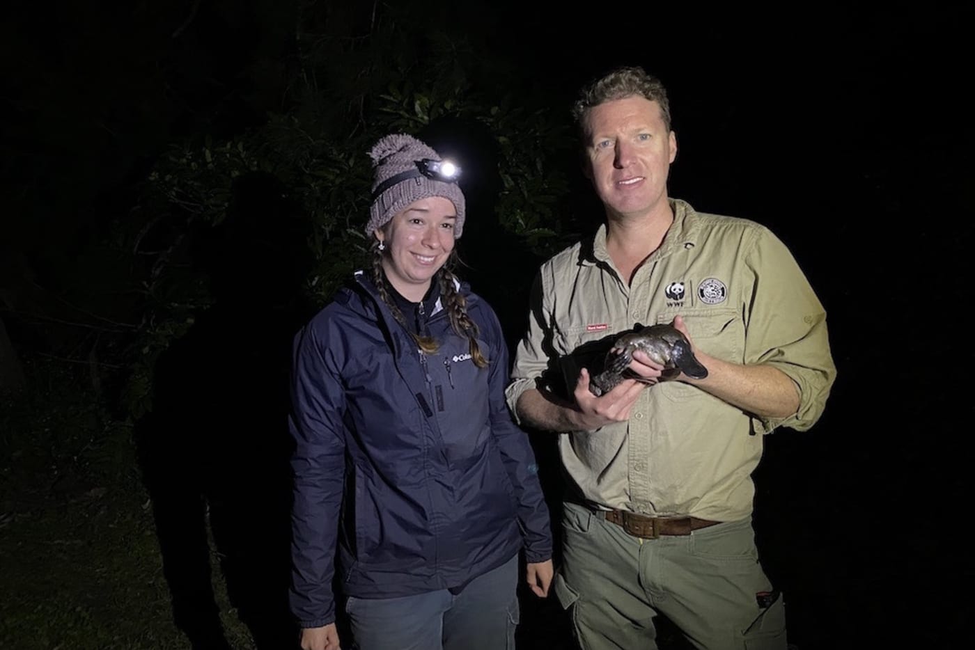 Rob Brewster holding a platypus during a habitat survey with UNSW platypus researcher Tahneal Hawke