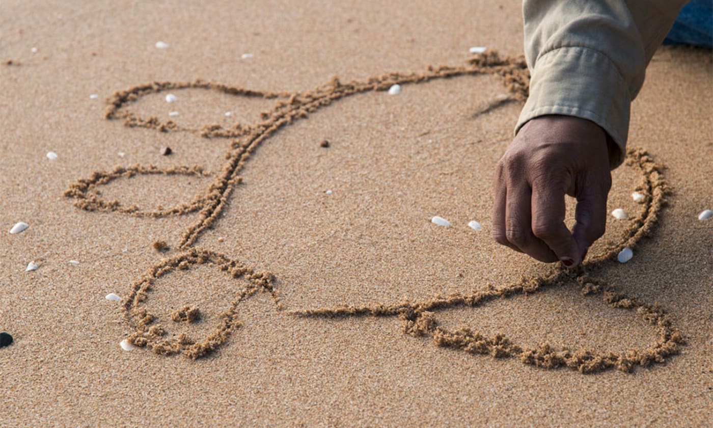 Gudjuda ranger Tracey Solomon, drawing turtle figure on sand, Alva Beach, North Queensland
