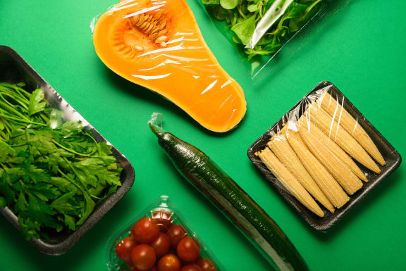 Fresh vegetables in plastic package. Zero waste, recycle concept. Plastic pollution. Green background