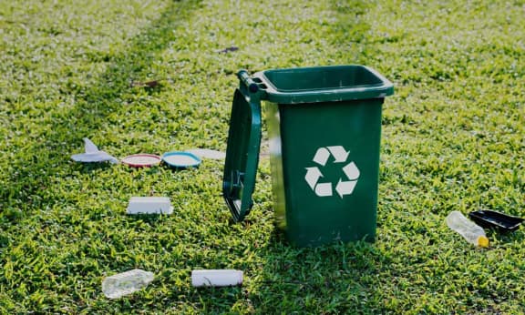 Green recycle bin surrounded by plastic bottles