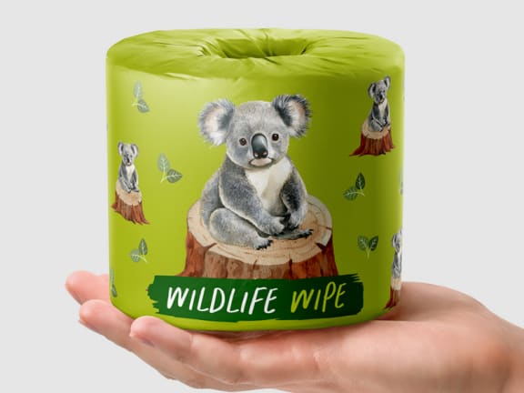 image of a hand holding out a roll of toilet paper. The toilet paper has light green wrapping with an image of a koala sitting on the stump of a recently chopped down tree. The text overlay underneath reads, "Wildlife Wipe".