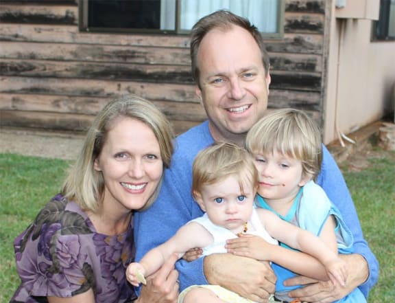 A family of a man, woman and two kids smile at the camera
