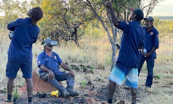 Nyikina Mangala Ranger Redman Charles using drone vision goggles to search for wiliji in caves on the Erskine Range while his Ranger team mates spot the drone overhead