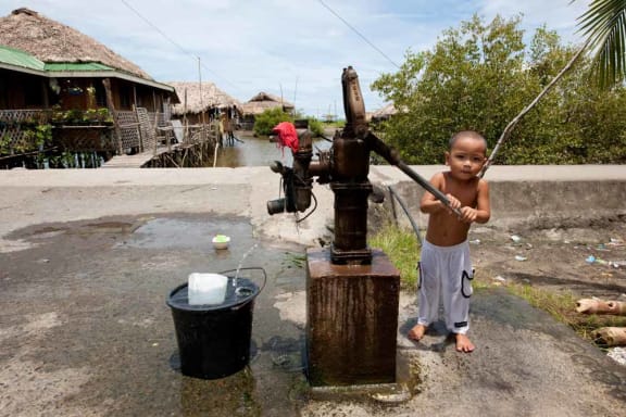 A little boy pumping out water for his bath in Donsol Sorsogon, Bicol, Philippines, May 2009