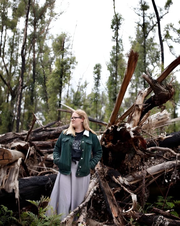 2023 Young Environmentalist of the Year Takesa Frank  standing in front of forest debris left from logging in North Brooman State Forest.