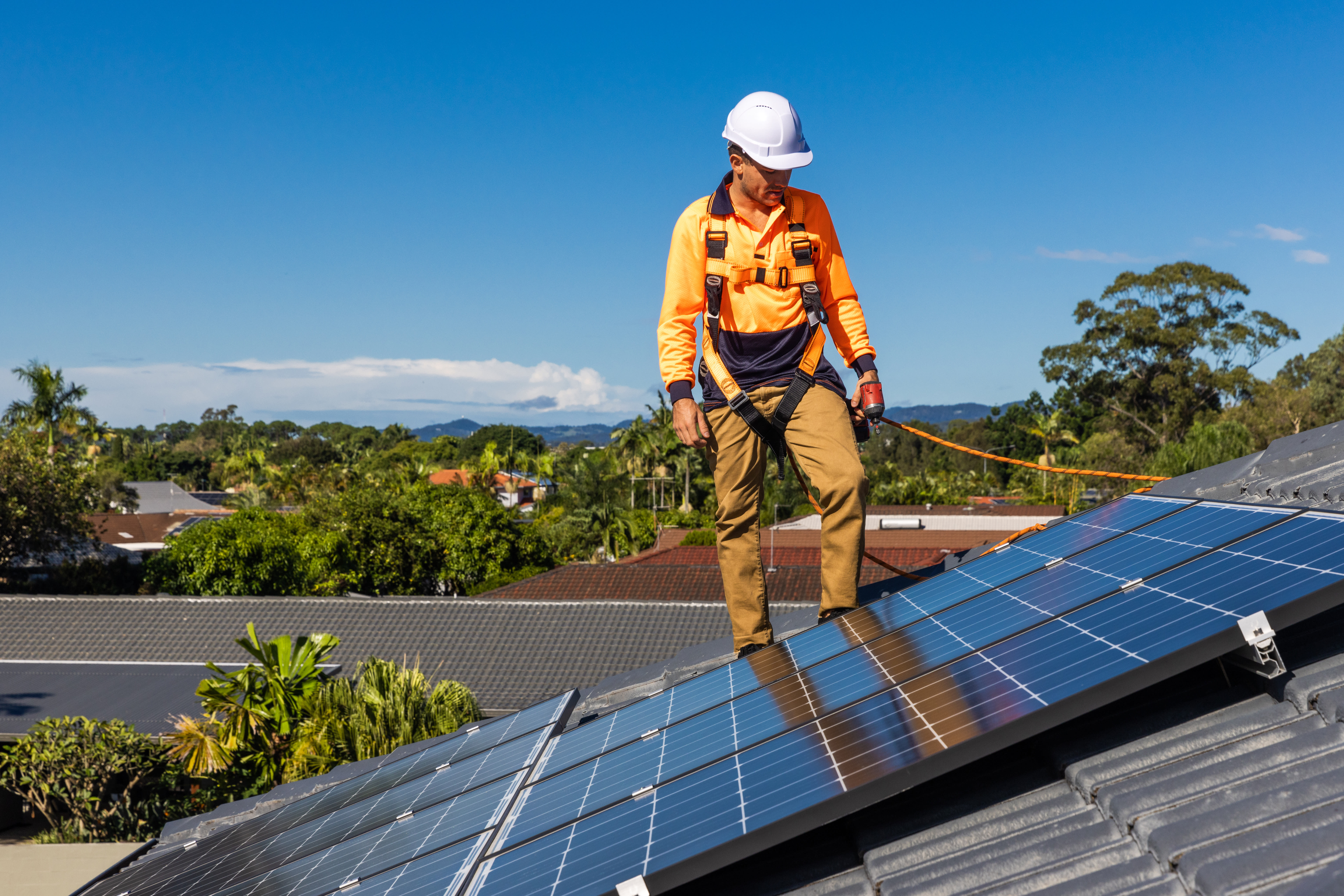 Worker installing solar panels on a residential rooftop.